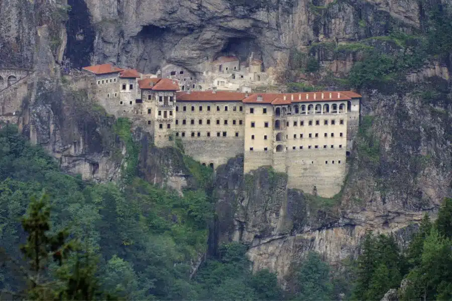 View of Sumela Monastery in Trabzon, dramatically perched on a misty cliff surrounded by dense forest.